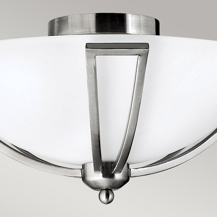 Vue rapprochée du bras central métallique fixé sur le verre blanc dépoli