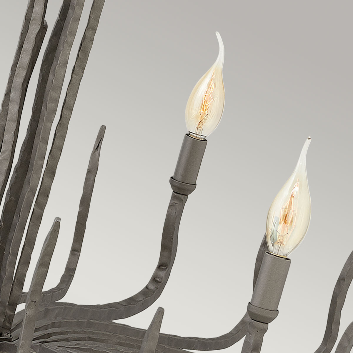 Détail des douilles et ampoules flammes sur les bras courbes du luminaire.