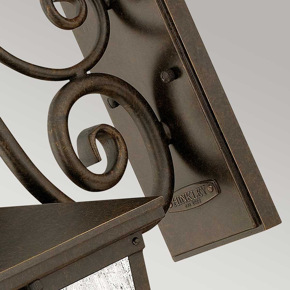 Gros plan sur la platine de fixation murale et sa finition bronze vieilli