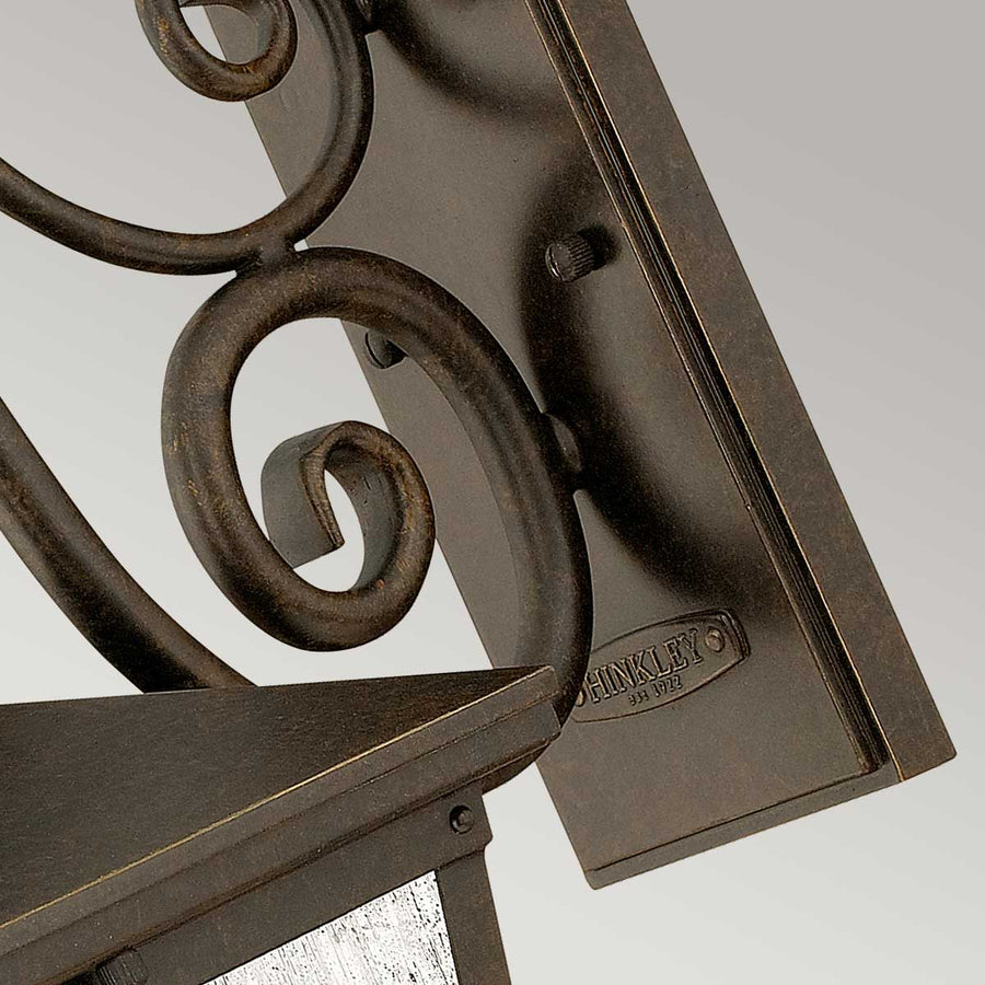 Gros plan sur la platine de fixation murale et sa finition bronze vieilli