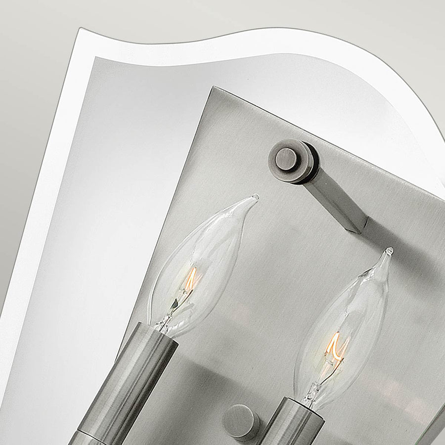 Vue rapprochée du haut de l'applique, verre biseauté et support nickel avec douilles apparentes.