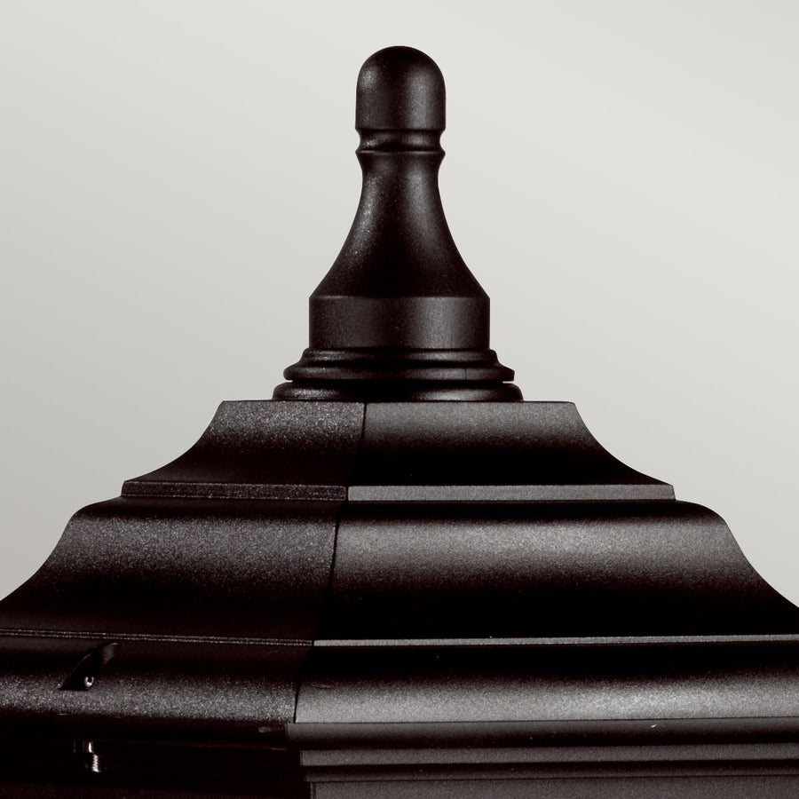 Gros plan sur le sommet mouluré et la pointe décorative noire du lampadaire