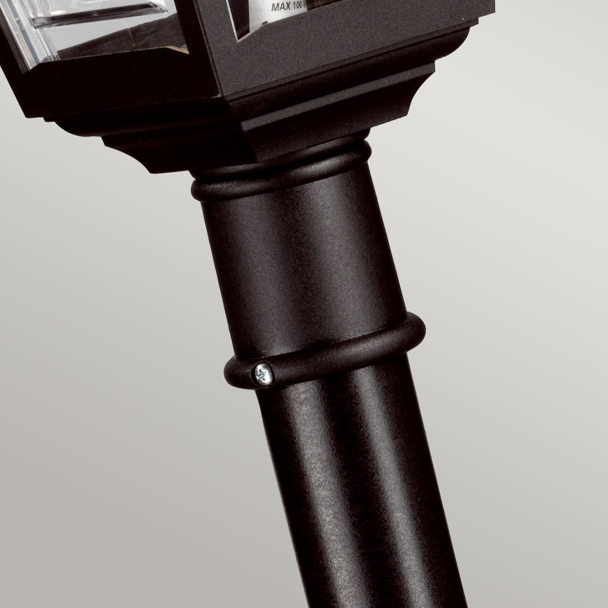 Détail du raccord cylindrique noir avec vis, sous la lanterne du lampadaire