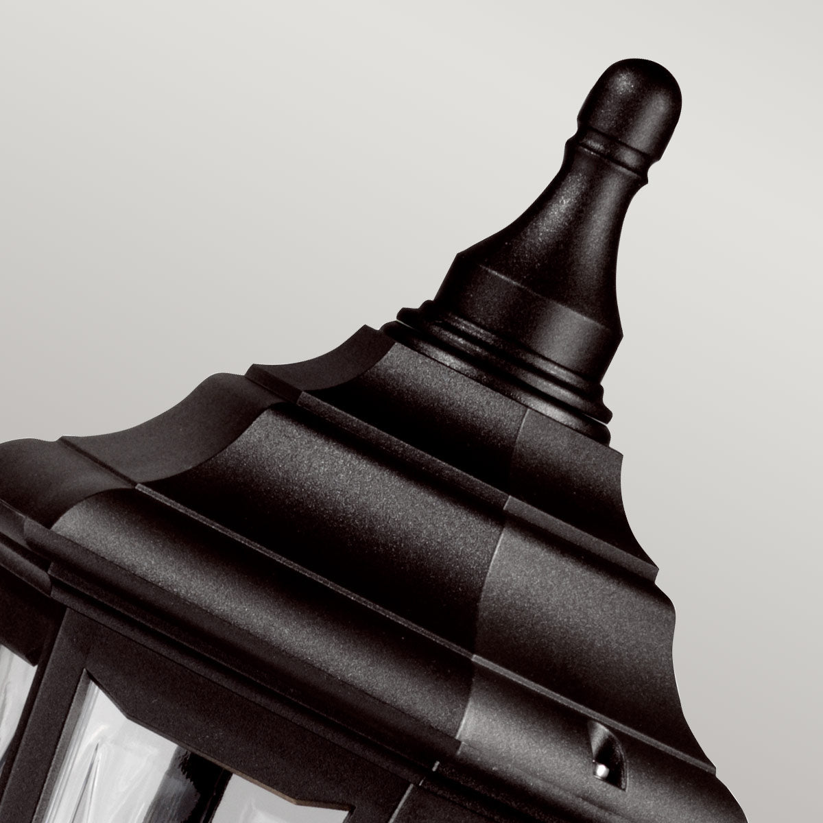 Gros plan sur le sommet noir ouvragé et la pointe décorative de la lanterne