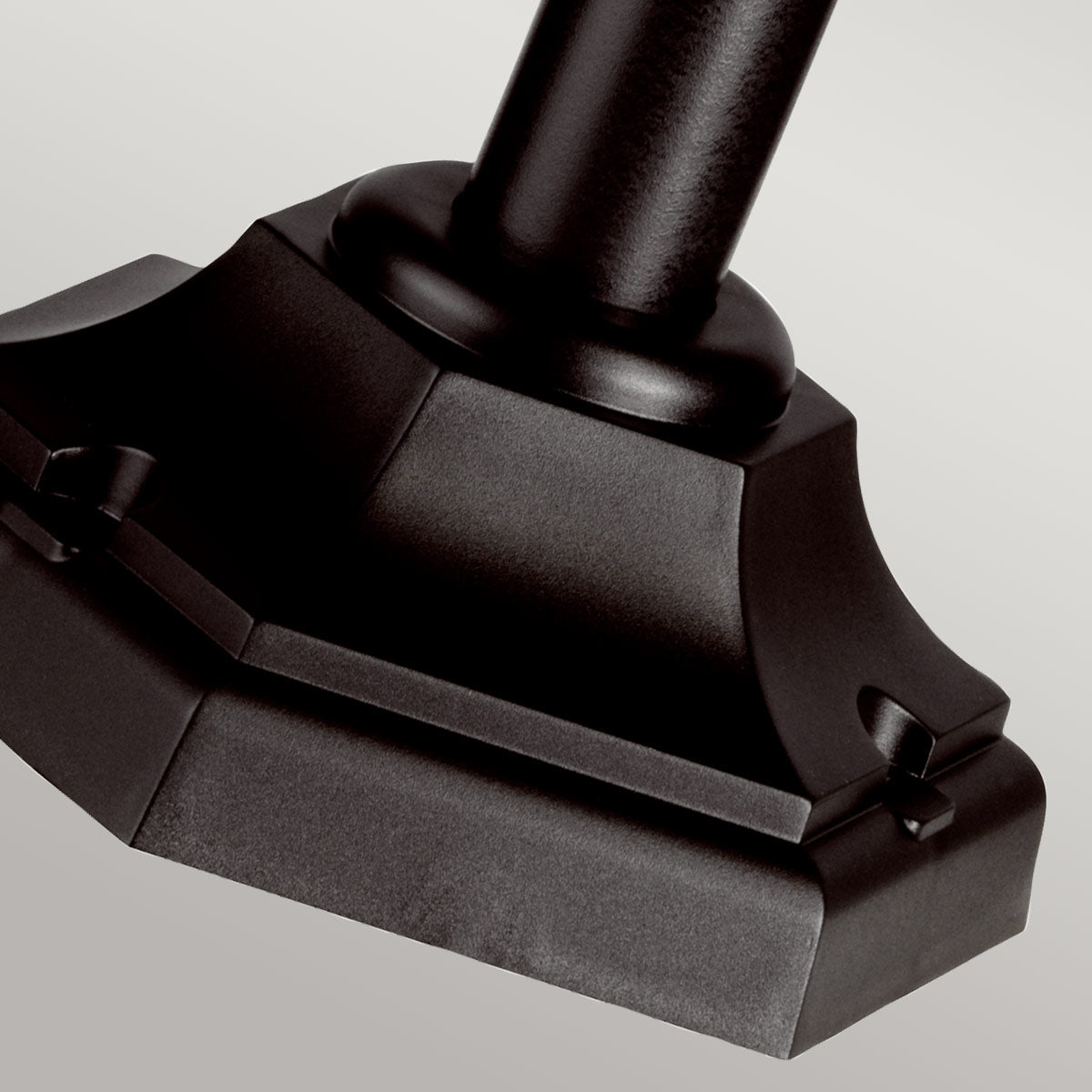 Gros plan sur la base octogonale noire et le pied cylindrique du lampadaire