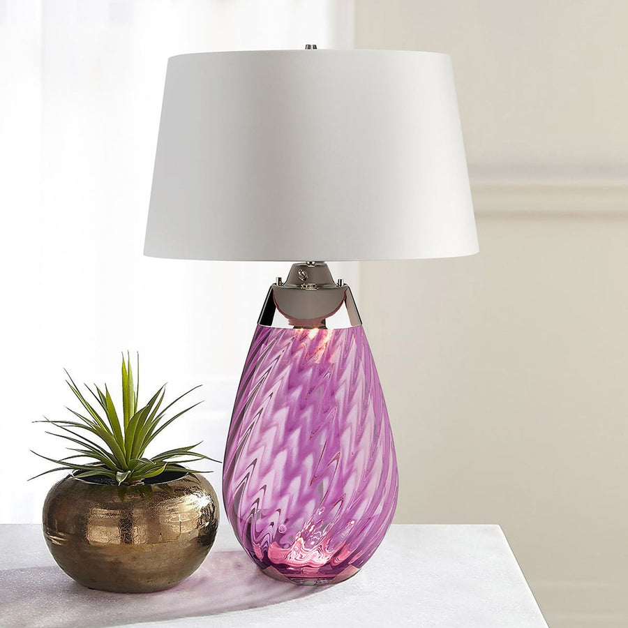 Lampe posée sur une table blanche, à côté d'une plante grasse dans un pot doré
