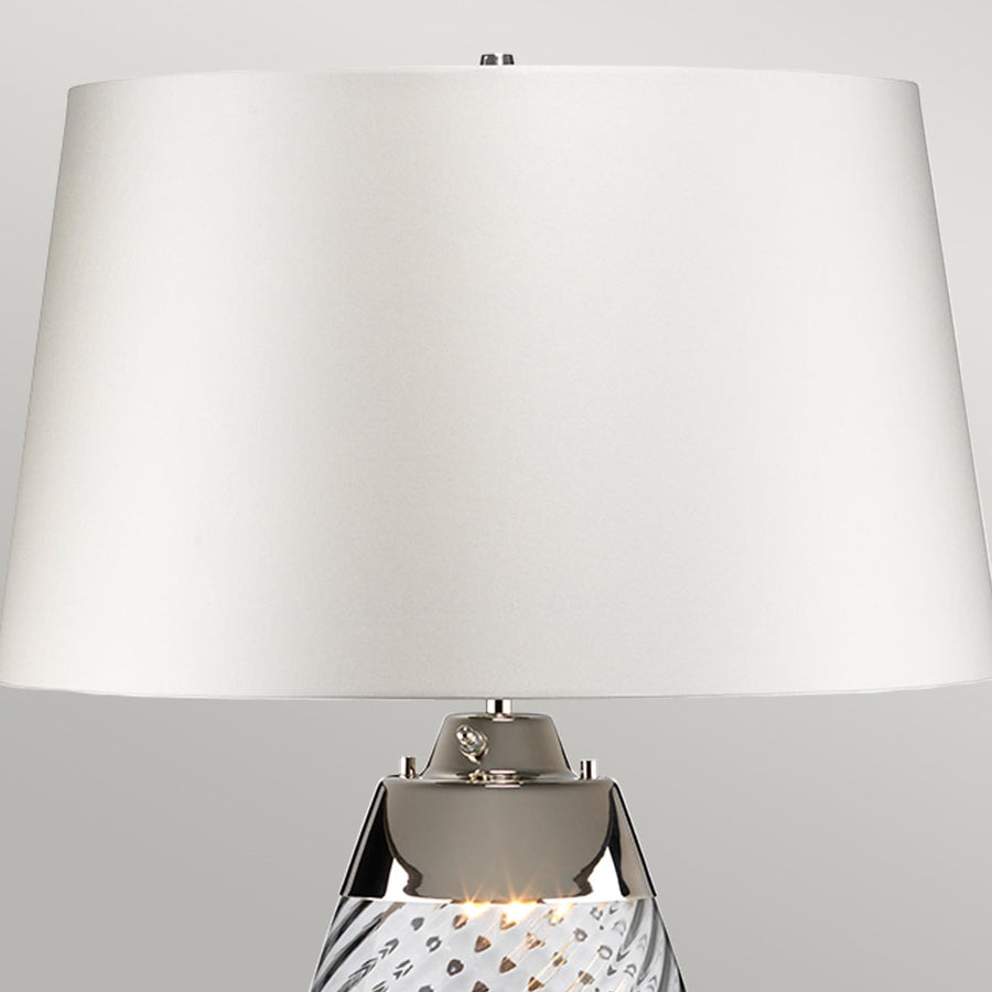 Gros plan sur l'abat-jour blanc et la bague chromée de la lampe