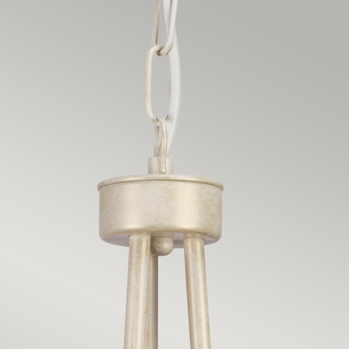 Gros plan sur la suspension à chaîne et le pavillon supérieur du lustre crème doré.