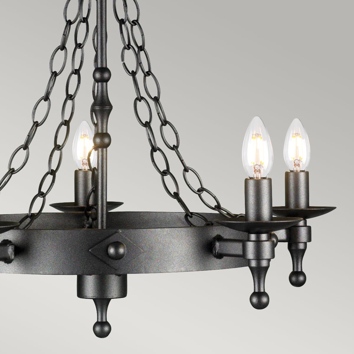 Gros plan sur le cercle central et les bras porte-bougies du luminaire en métal texturé.