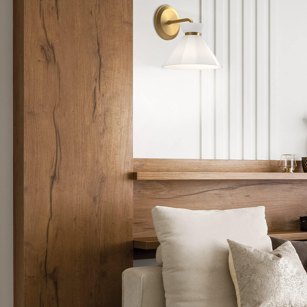 Mise en ambiance de l'applique murale dorée au-dessus d'un lit en bois clair