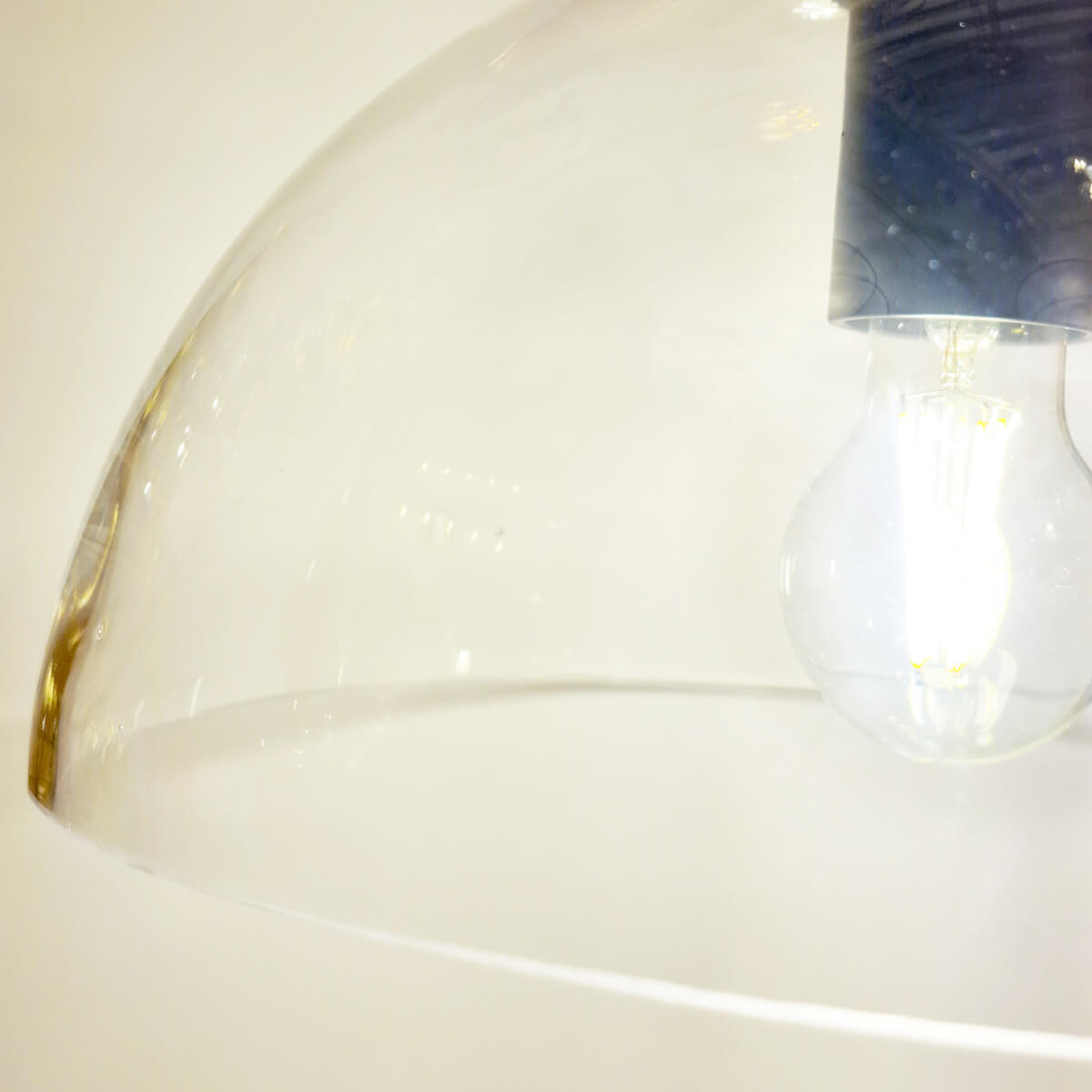 Détail du bord de l'abat-jour en verre transparent et de l'ampoule allumée en gros plan