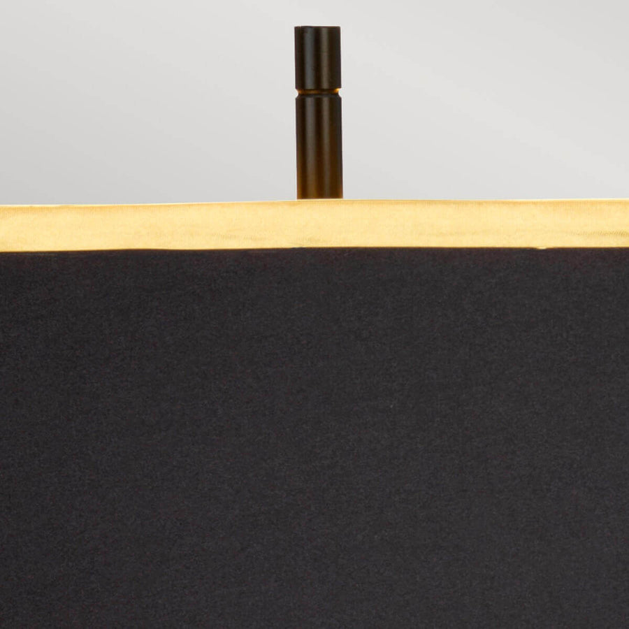 Détail du sommet avec finition noire cylindrique dépassant au-dessus de l’abat-jour doré.