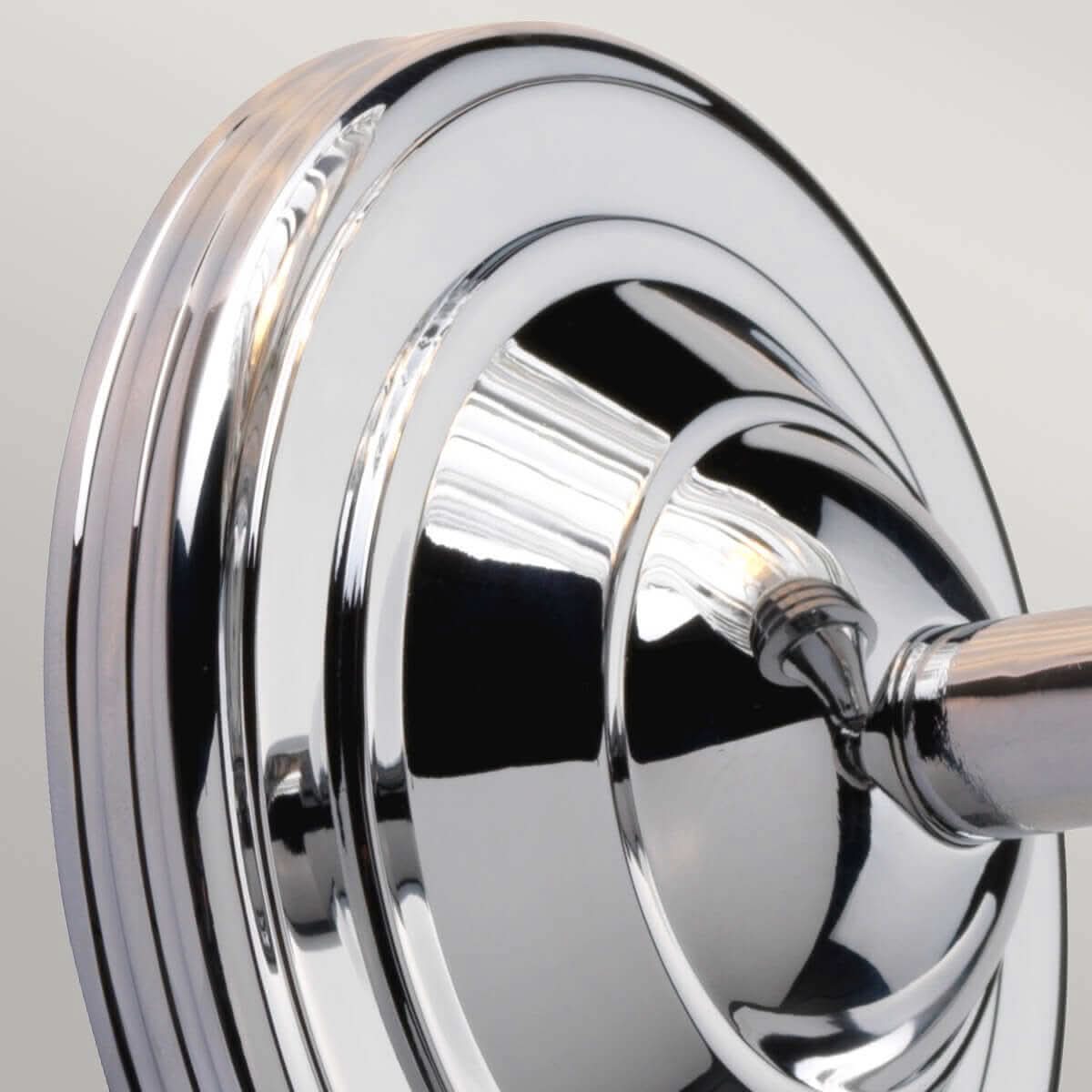 Détail de la platine ronde en chrome poli fixée au mur, reflets marqués