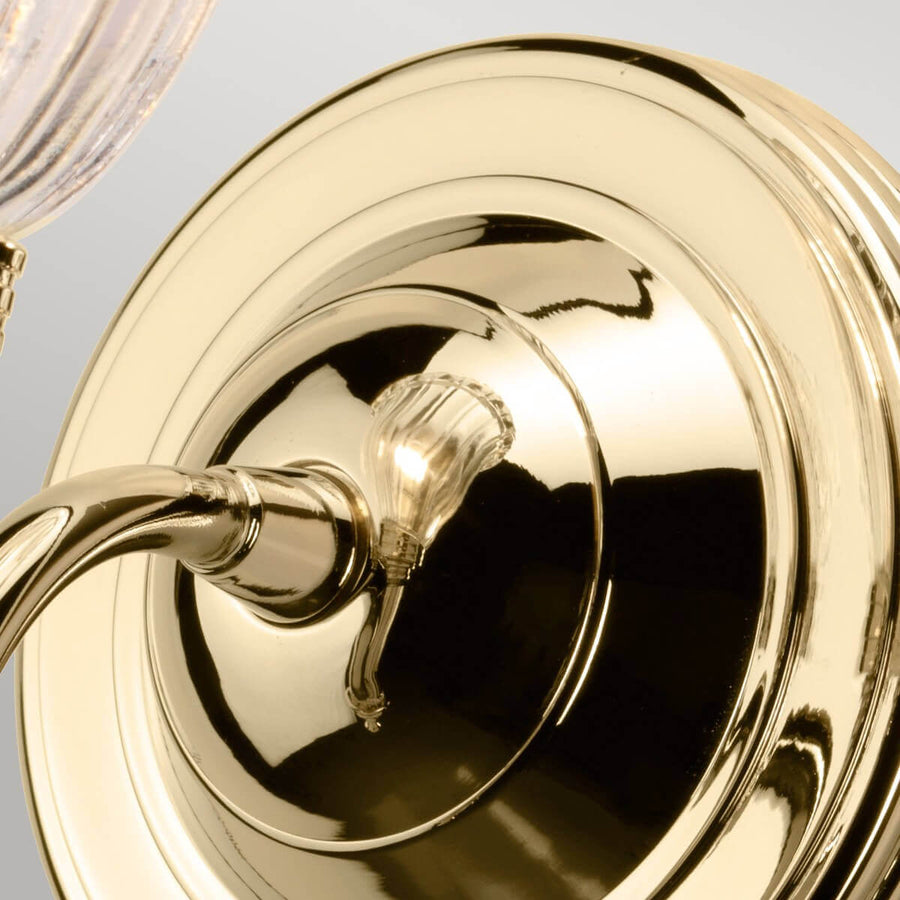 Gros plan sur la platine ronde en laiton poli fixée au mur, reflets brillants