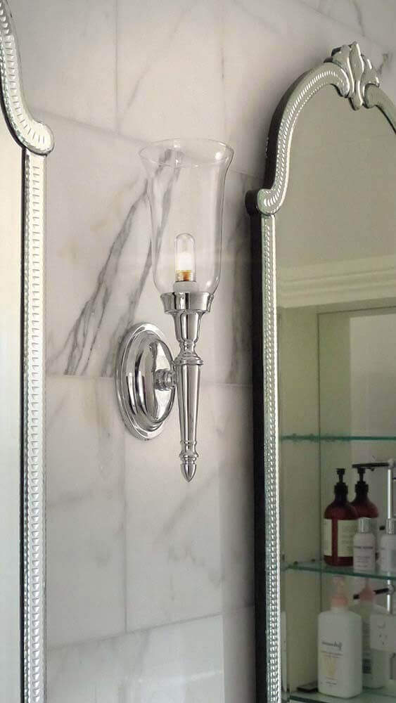Applique allumée installée dans une salle de bain en marbre, près d'un miroir