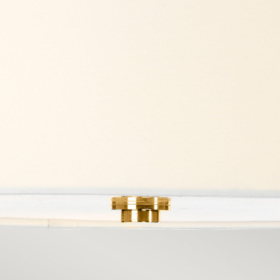 Détail de la petite fixation dorée sous l'abat-jour blanc du luminaire