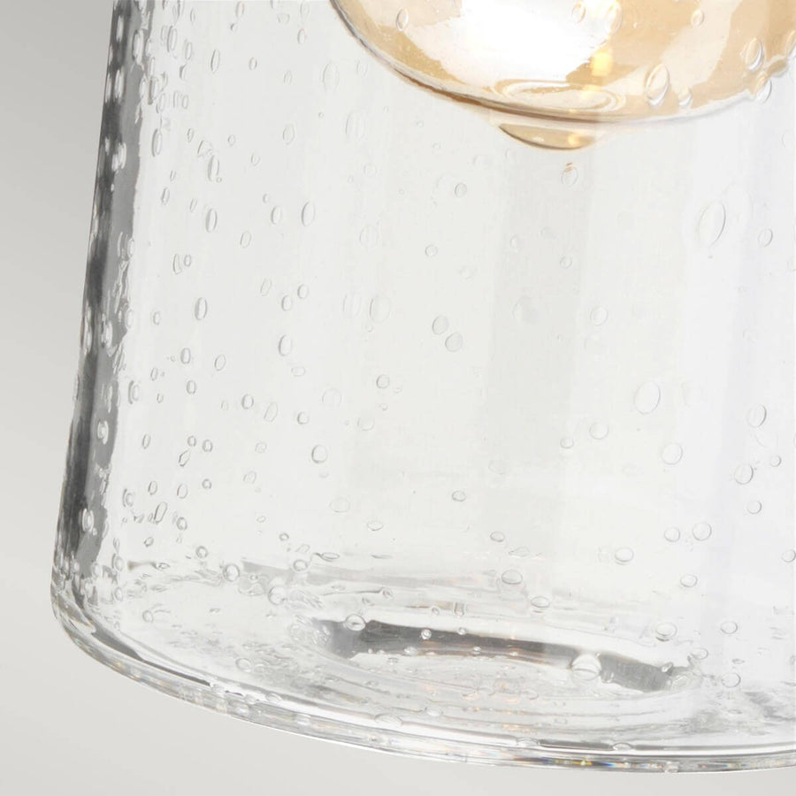 Détail du verre moucheté transparent laissant voir l'ampoule dorée illuminée