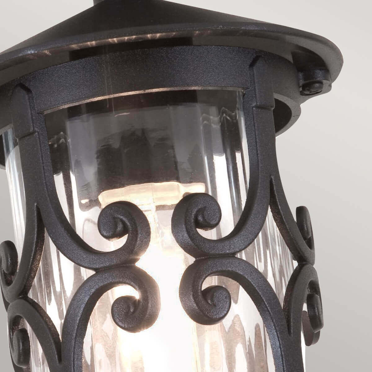 Gros plan sur les volutes métalliques noires devant le verre cannelé