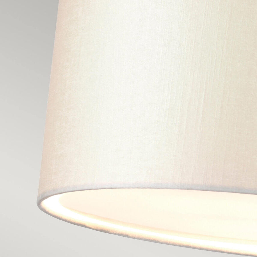 Gros plan sur le bord inférieur de l'abat-jour en tissu crème légèrement éclairé