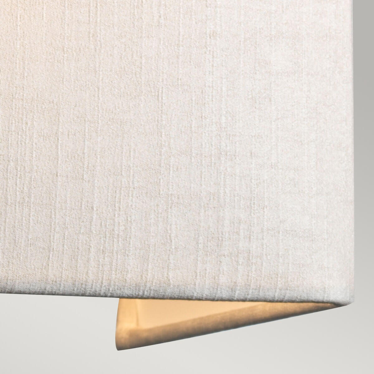 Gros plan sur la texture tissée crème et la base dorée du luminaire