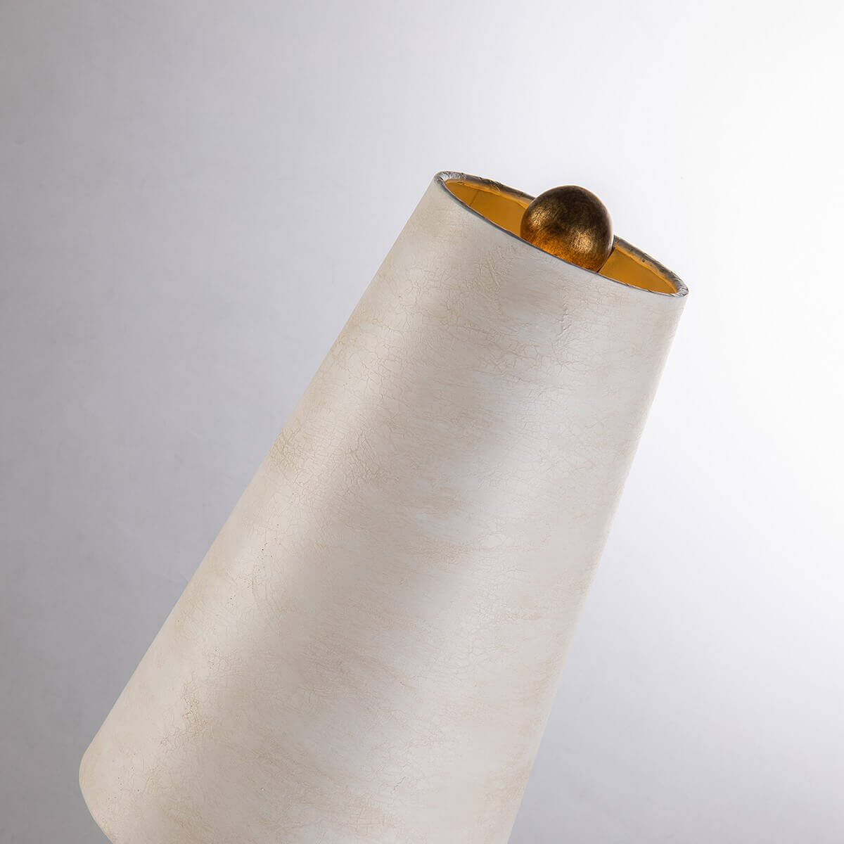 Détail du sommet de l'abat-jour crème et de la bille dorée qui le surmonte.