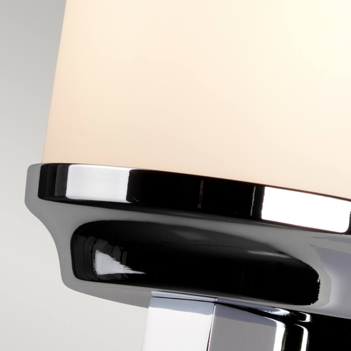 Détail du cerclage chromé brillant maintenant le diffuseur cylindrique en verre opalin
