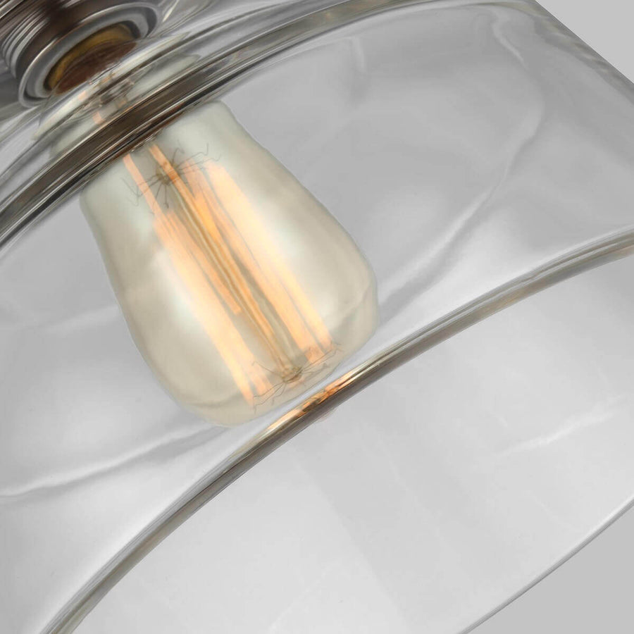 Détail de l'ampoule à filament doré allumée à travers l'abat-jour transparent