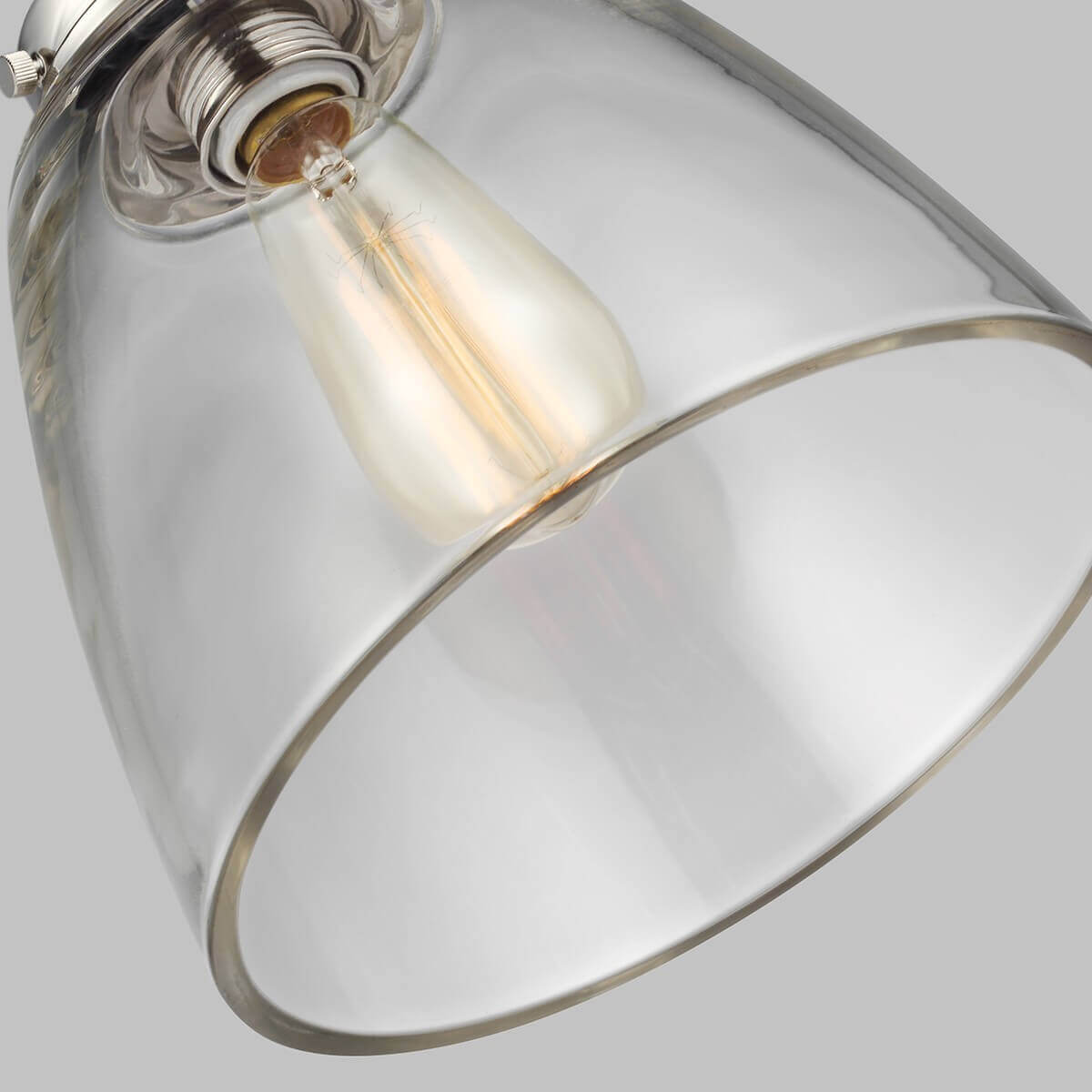 Gros plan sur l'abat-jour en verre transparent et l'ampoule à filament allumée à l'intérieur.