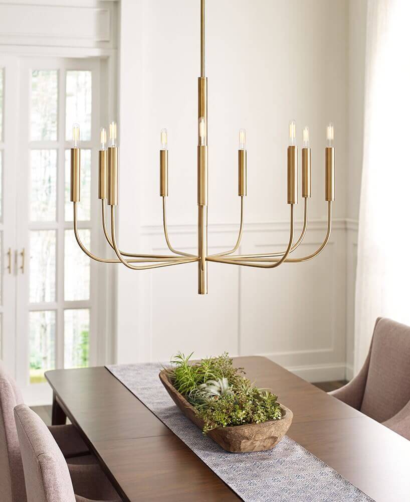Suspension en laiton installée au-dessus d'une table de salle à manger avec centre de table végétal.