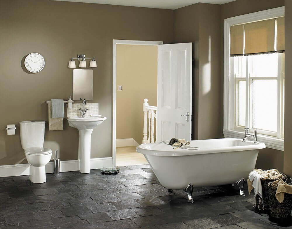 Mise en ambiance dans une salle de bain classique avec baignoire îlot et applique au-dessus du lavabo.