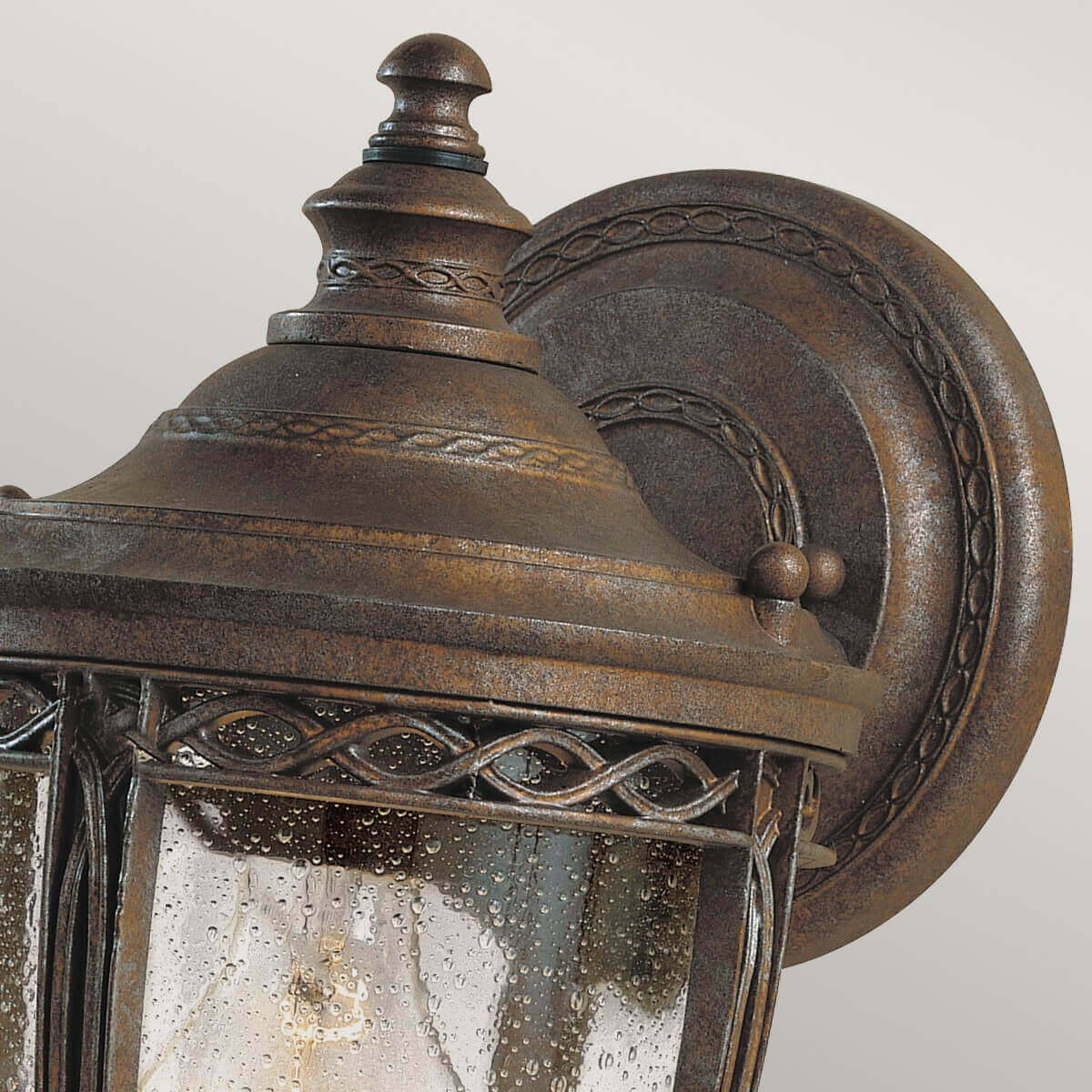 Gros plan sur le support mural rond et la finition bronze martelé du luminaire.