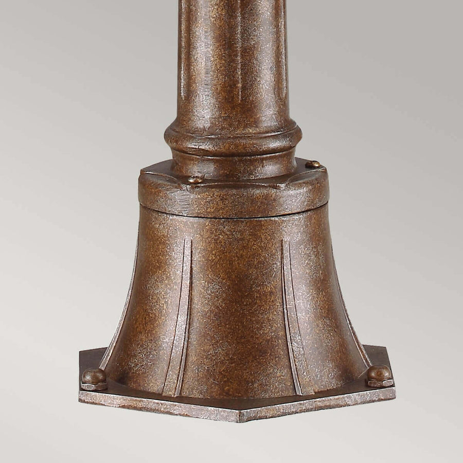 Détail de la base moulurée et fixations boulonnées du pied de lampadaire extérieur.