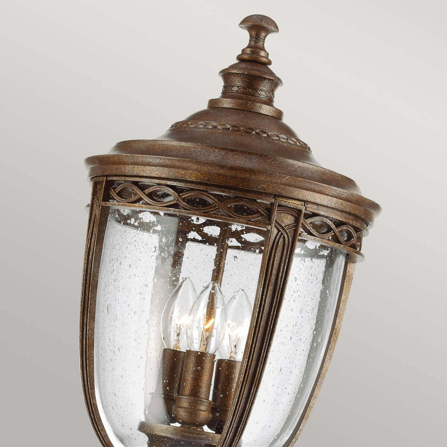 Gros plan sur la lanterne, verre couvert de gouttes, trois ampoules allumées, cadre bronze.