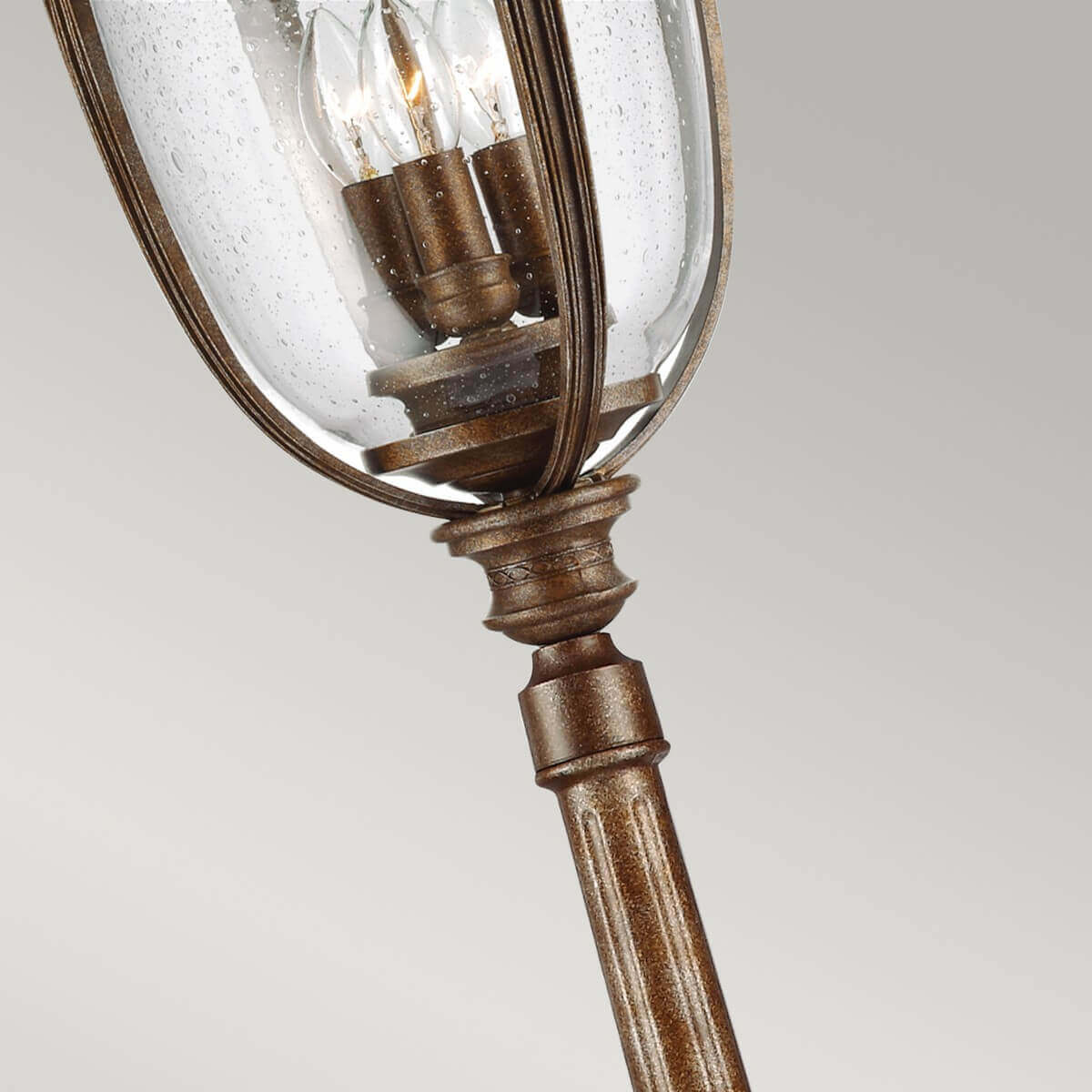 Vue rapprochée de dessous, lanterne en verre mouillé, trois ampoules bougies et détails du bronze.