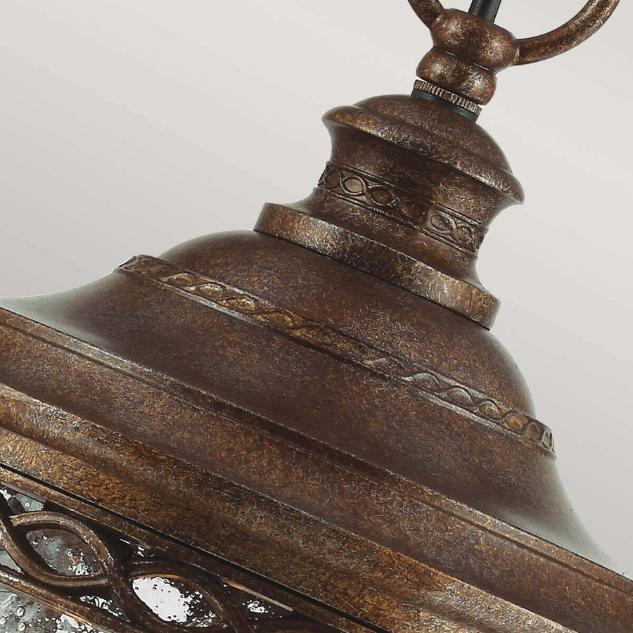 Gros plan sur le sommet mouluré et les anneaux décoratifs en bronze vieilli.
