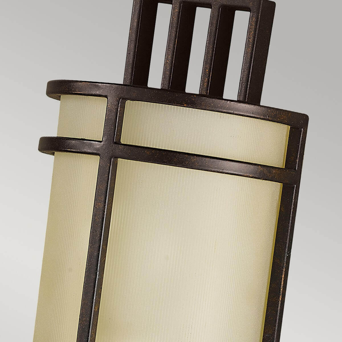 Gros plan sur la grille métallique, la finition bronze vieilli et le verre texturé