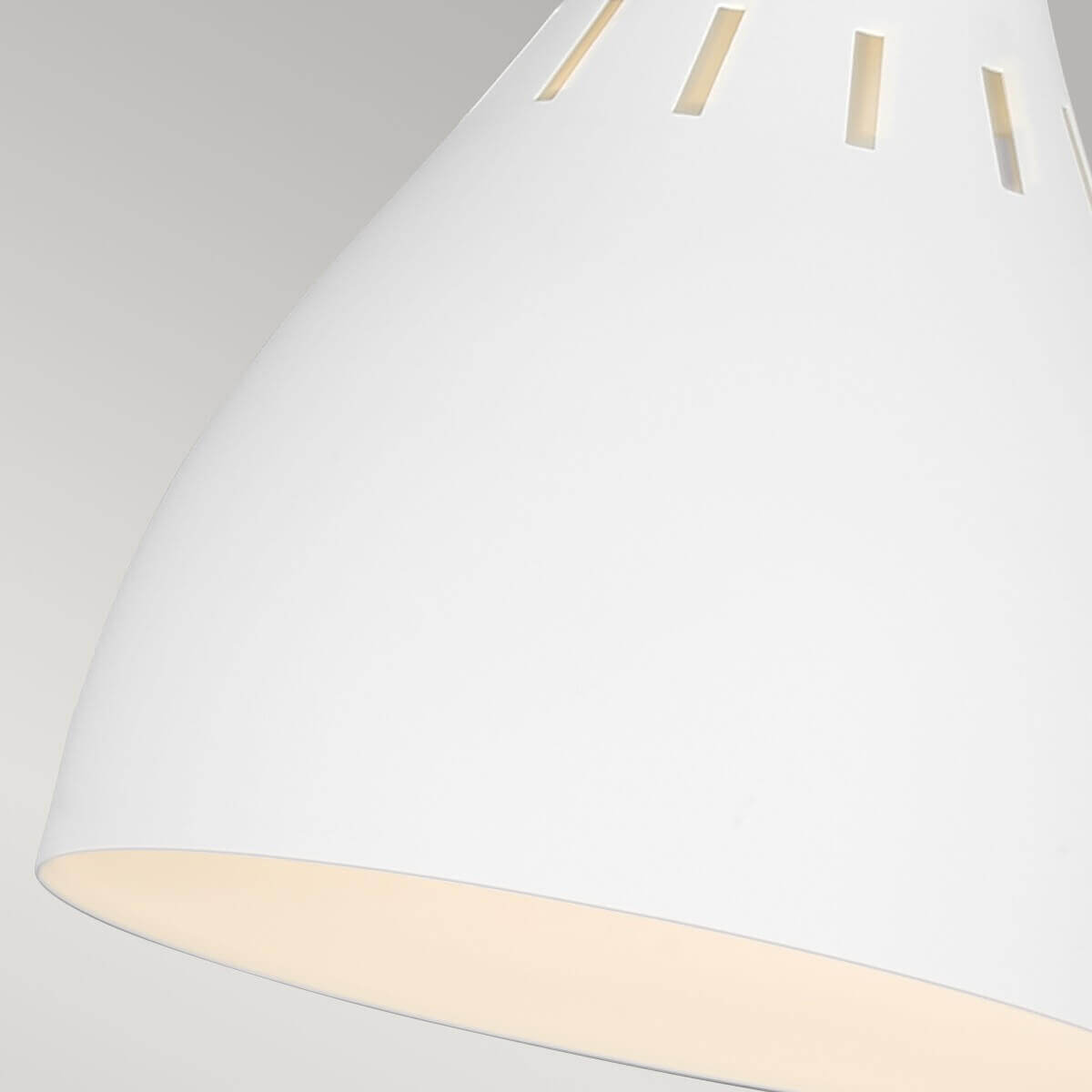 Gros plan de l'abat-jour blanc percé de fentes verticales laissant filtrer la lumière