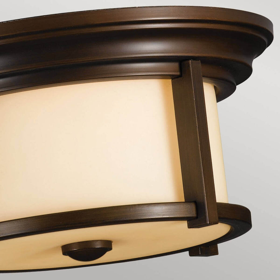 Détail rapproché de la monture bronze et du verre cylindrique ambré du plafonnier