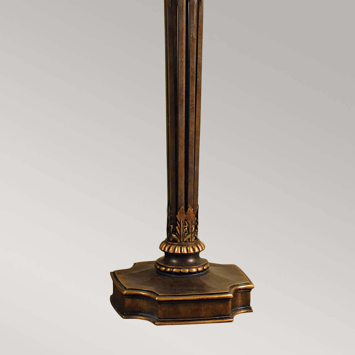 Détail de la base ouvragée dorée avec socle octogonal et motif de feuilles.