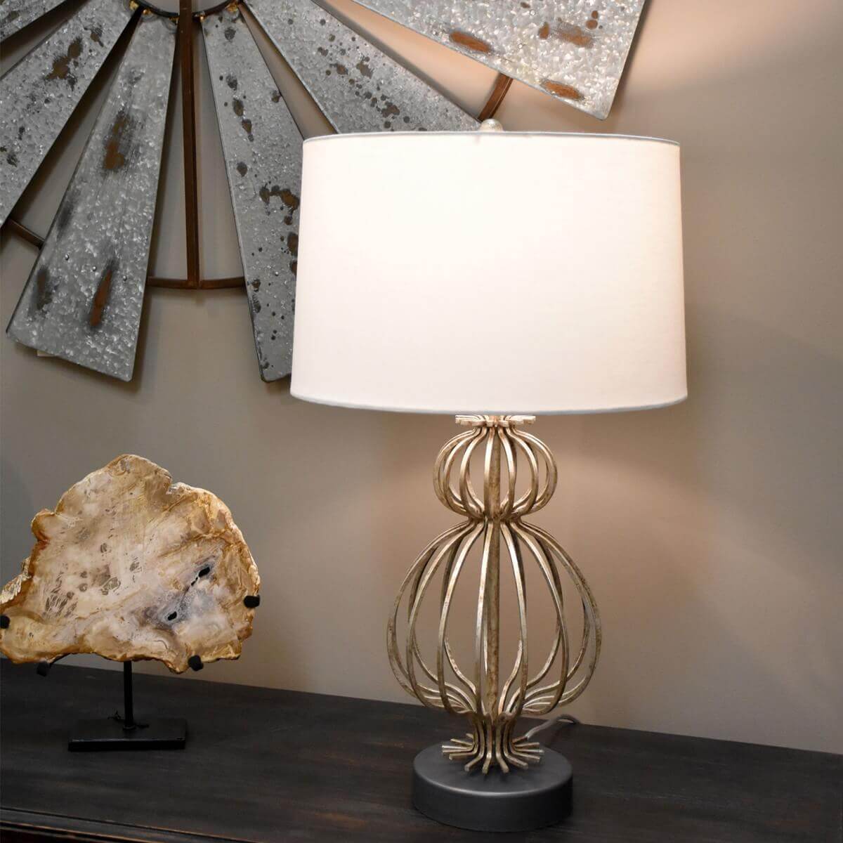 Mise en ambiance : lampe allumée sur un meuble en bois, décor mural en métal