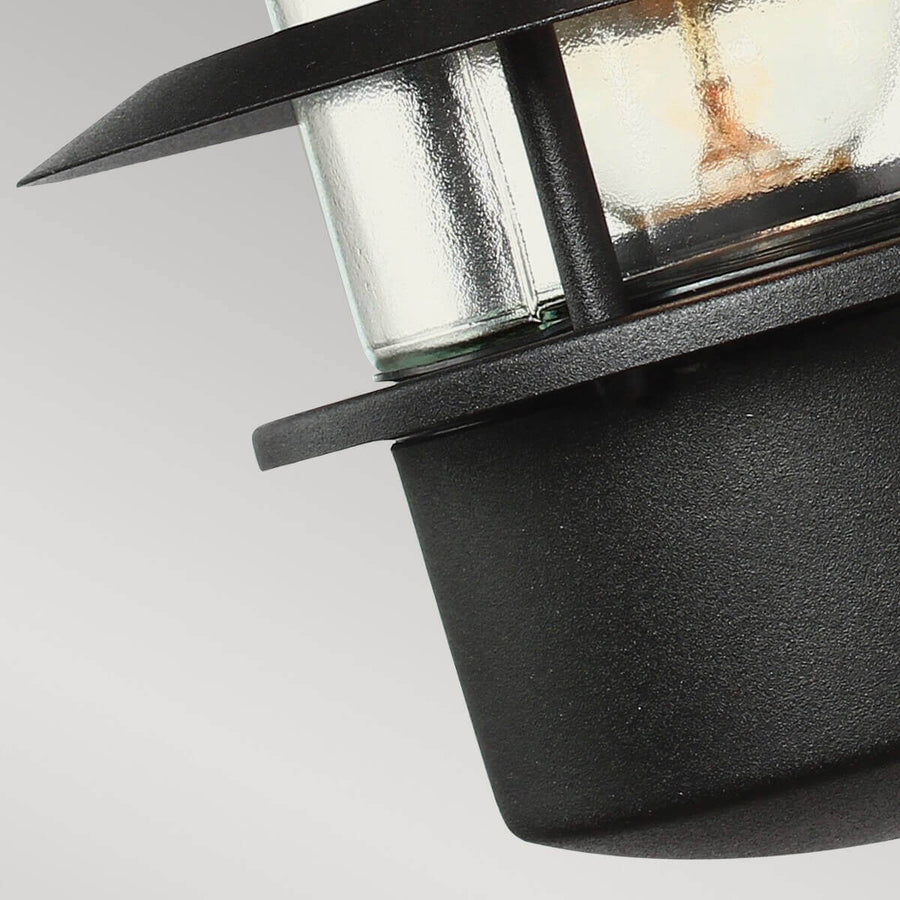 Gros plan du bas du luminaire, verre strié et collerette métallique noire