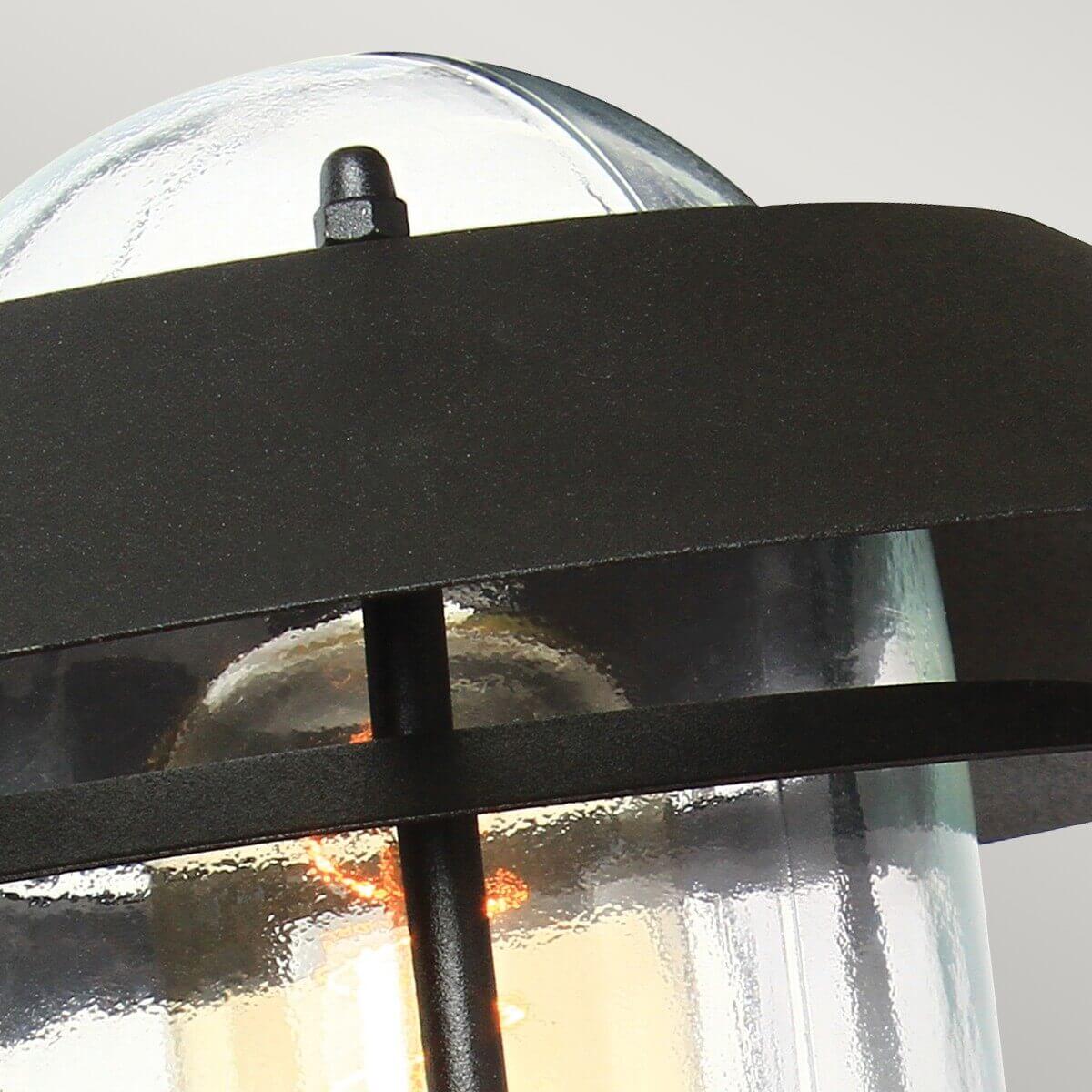 Détail du sommet en verre bombé et de la vis maintenant le chapeau métallique noir.