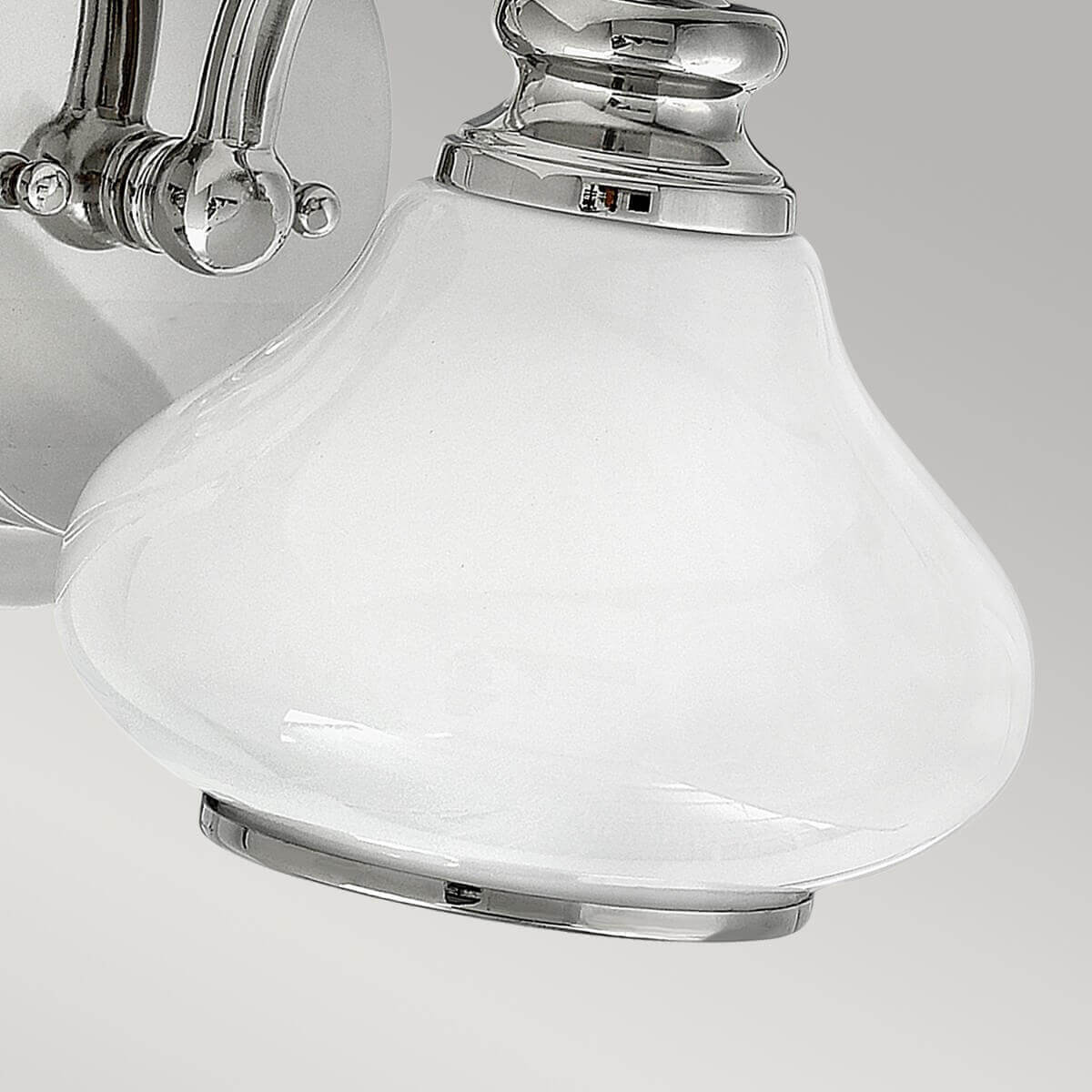 Vue rapprochée du bas du globe en verre blanc et de sa bague chromée.