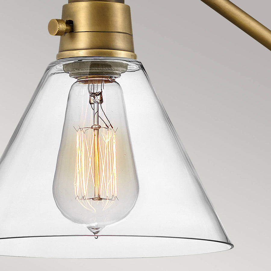 Gros plan sur l'abat-jour conique en verre laissant voir l'ampoule à filament.