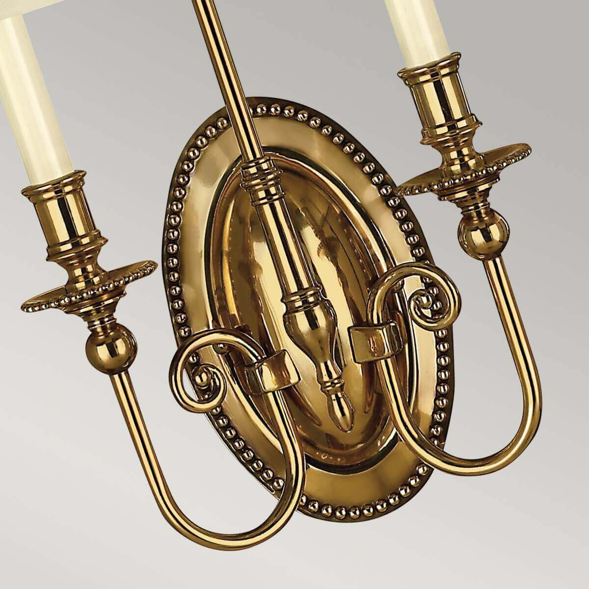 Détail de la platine ovale perlée et des bras recourbés en laiton poli