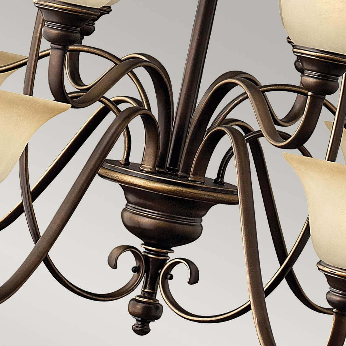 Vue rapprochée du bas du lustre avec ses volutes et sa finition bronze.
