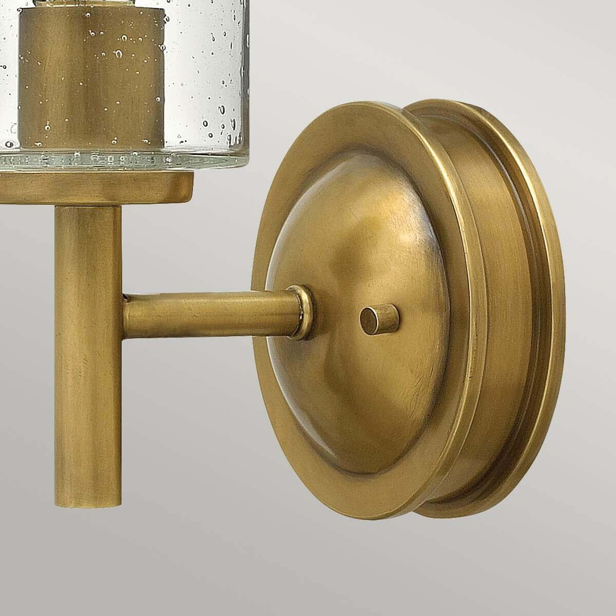 Détail de la platine ronde en laiton brossé fixée au mur