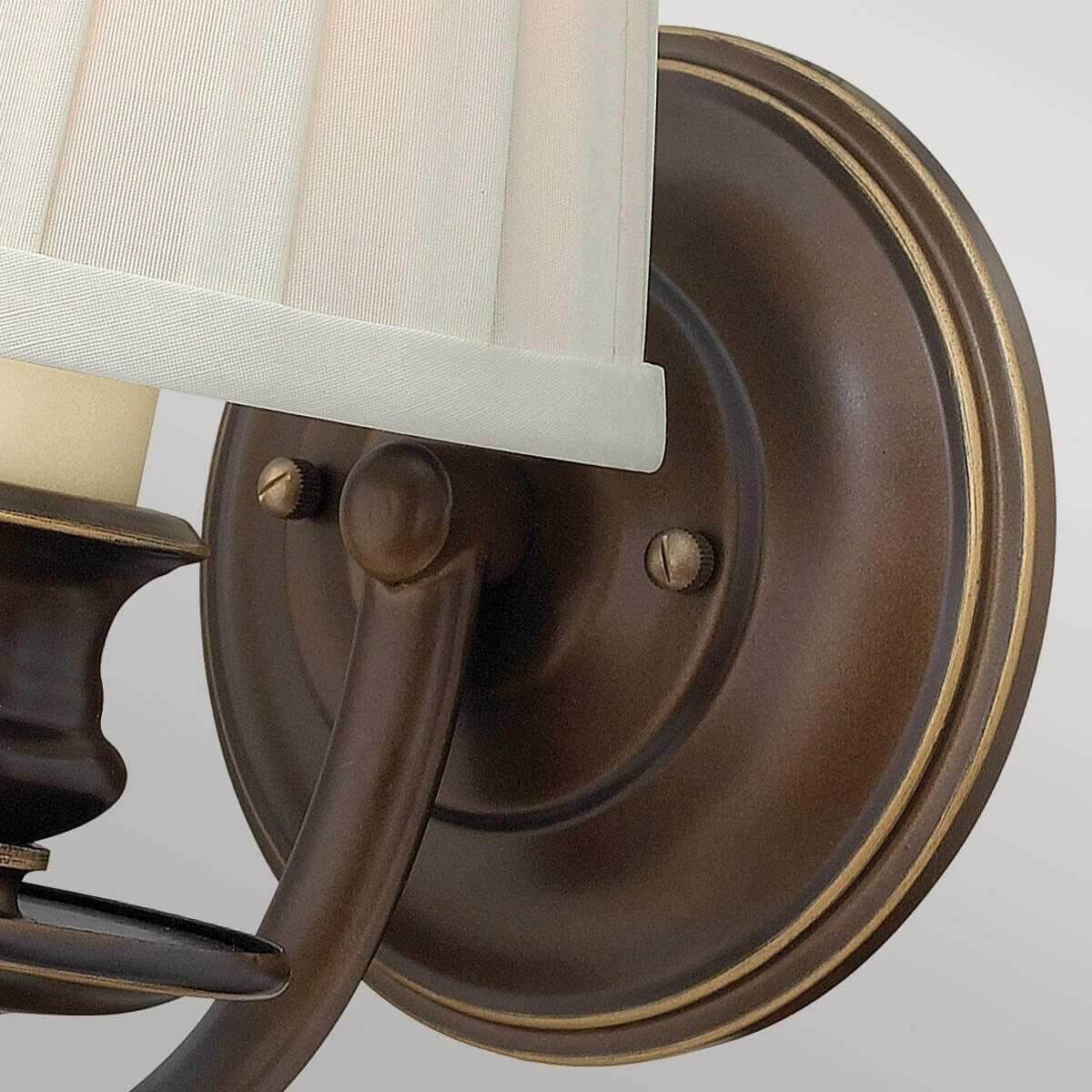 Gros plan sur la platine murale ronde en bronze et ses vis de fixation