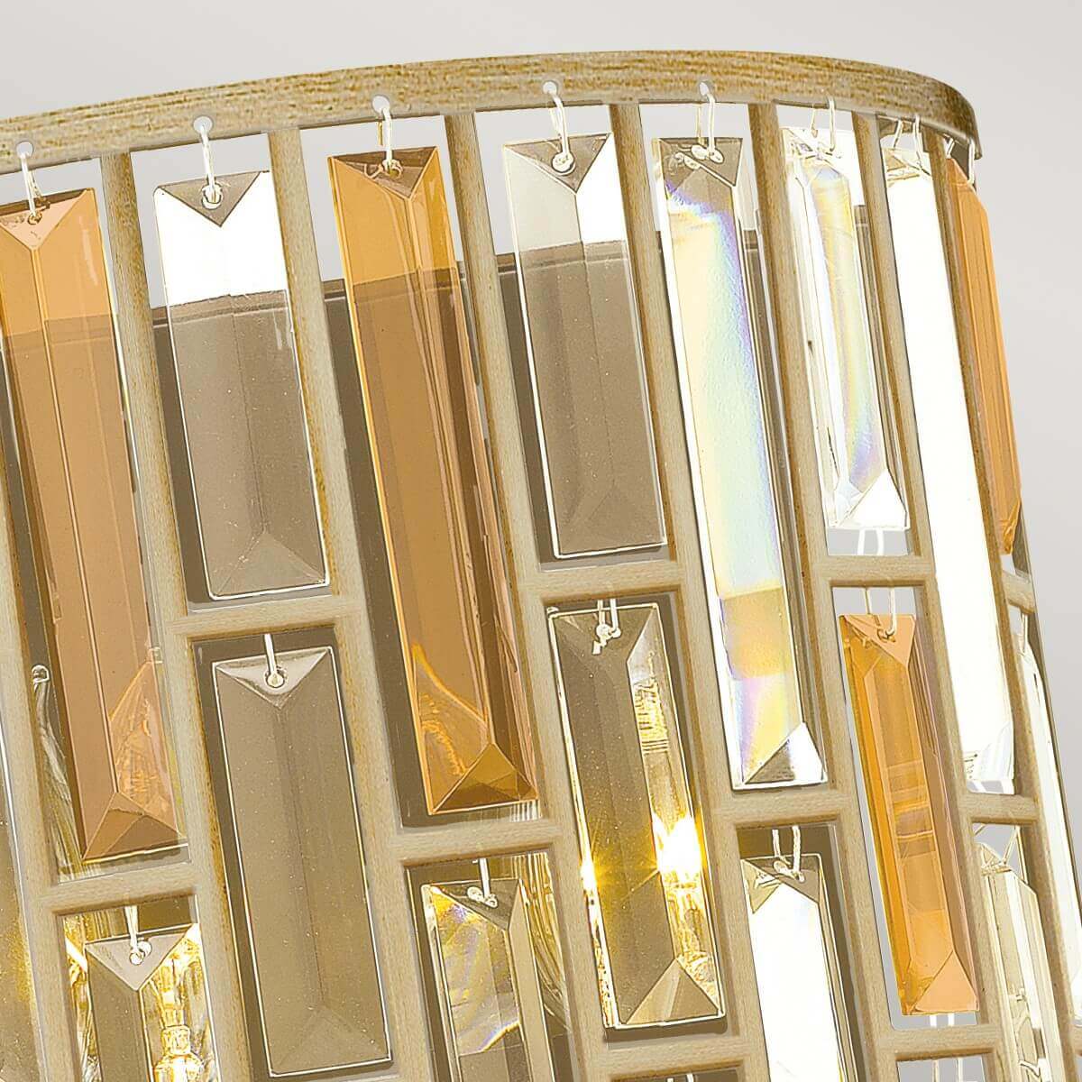 Détail du haut de l’applique, attaches métalliques et cristaux facettés suspendus.