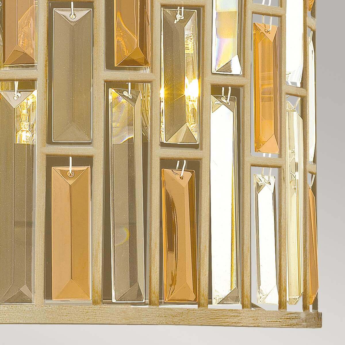 Gros plan sur la base, grille ajourée et pendentifs rectangulaires en cristal ambré.